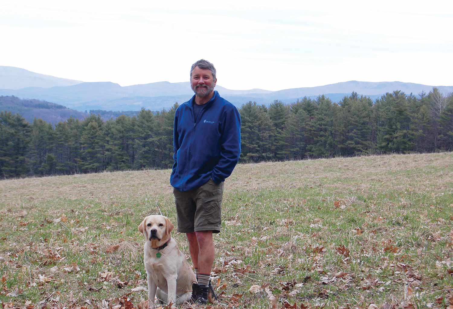 Hawk Metheny standing in a field with his lab looking at the camera and smiling