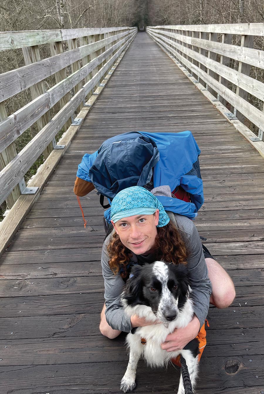 A person posing with their dog on a wooden bridge 