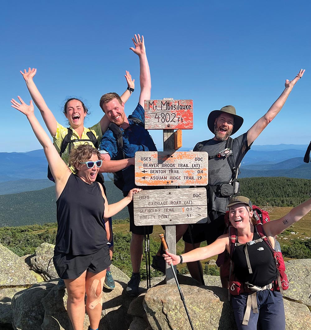 5 People posing next to Mt. Moosilauke summit sign