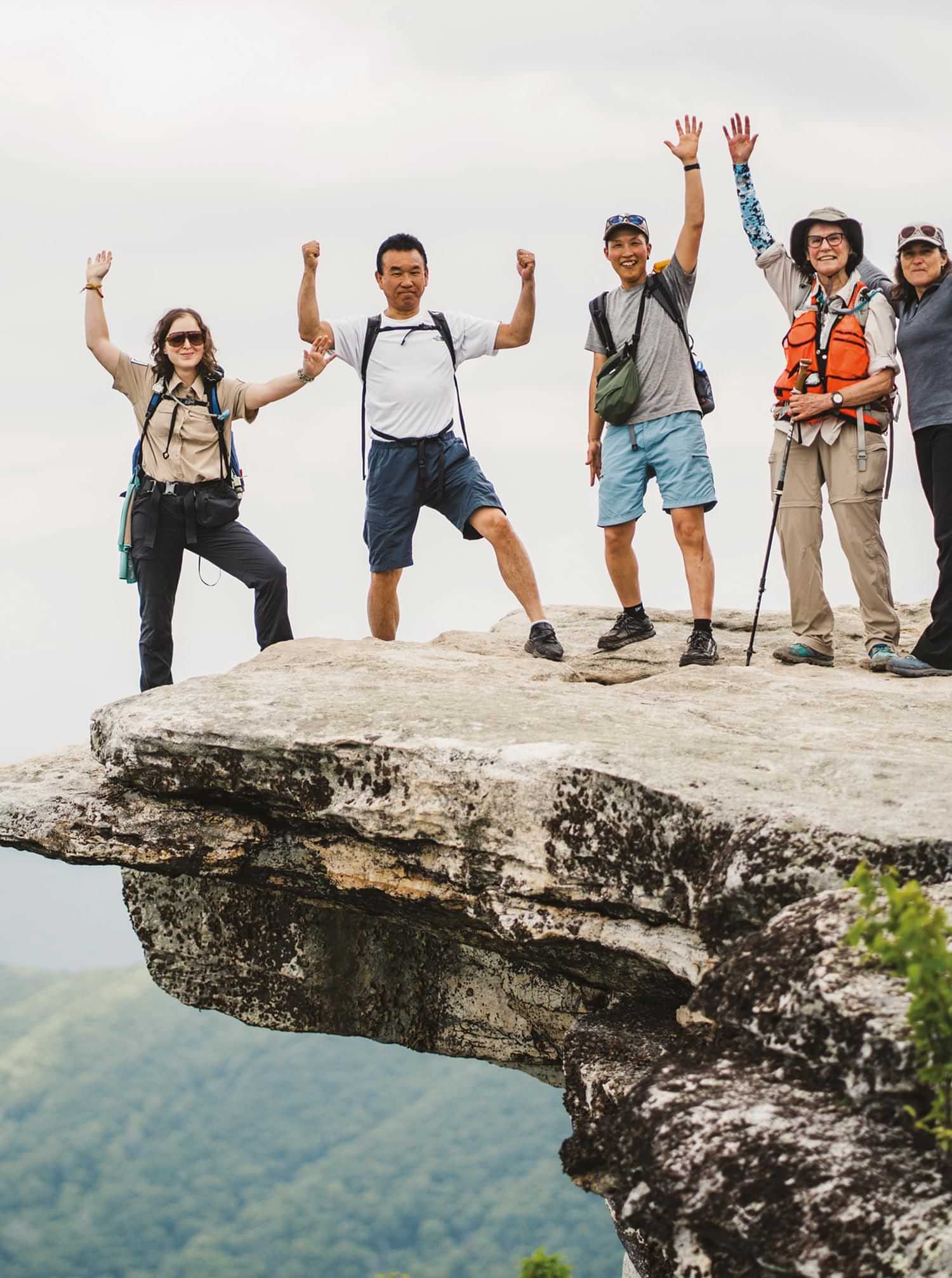 ATC ridge-runner Suzanne Neal, Hiroshi Kimura, Yukiko Satoh, Diana Christopulos of the Roanoke A.T. Club, and Laura Belleville of the ATC all smile while they stand atop a jutting cliff at McAfee Knob during their journey along the A.T.