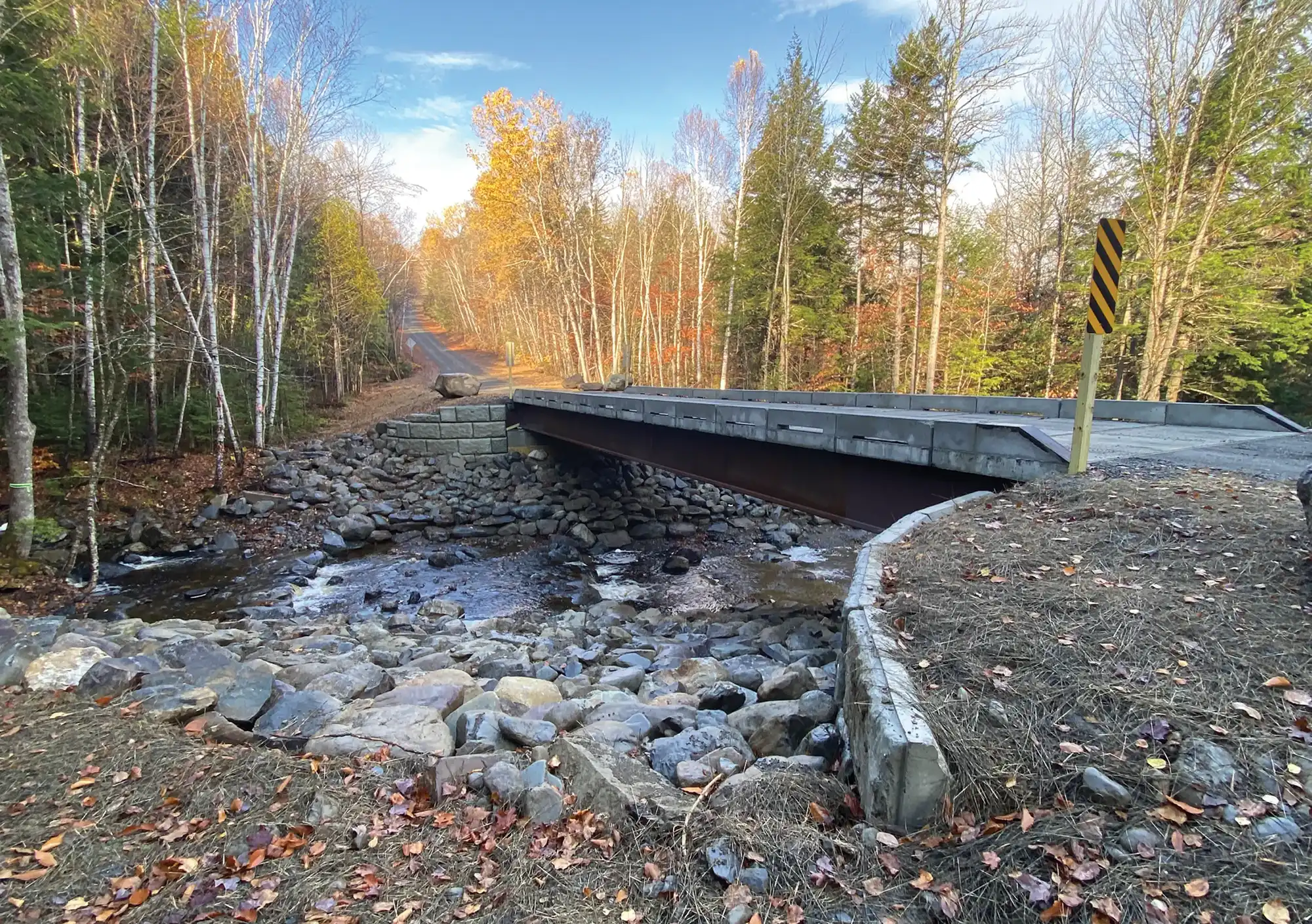 Concrete bridge extending over rocky brook