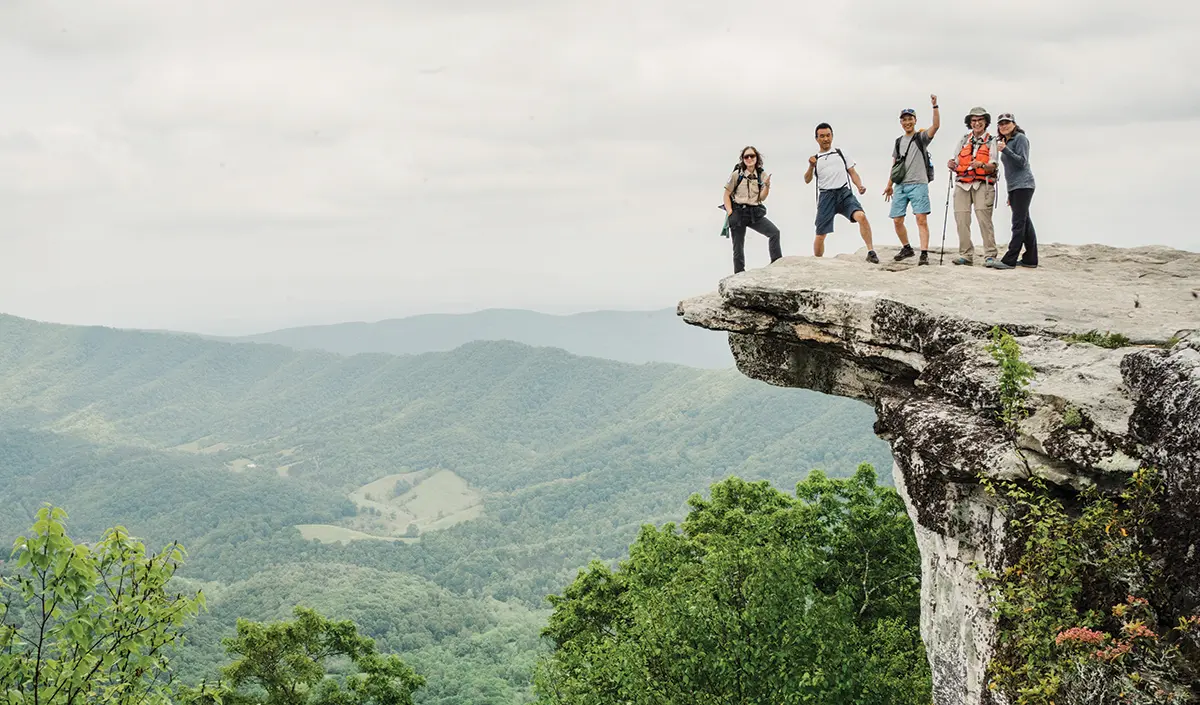 Landscape photograph view of staff from the ATC and the National Park Service alongside Diana Christopulos in 2023 on an overcast day as Diana was one of the RATC volunteers who accompanied representatives from Japan’s Shinetsu Trail Club on a hike to McAfee Knob