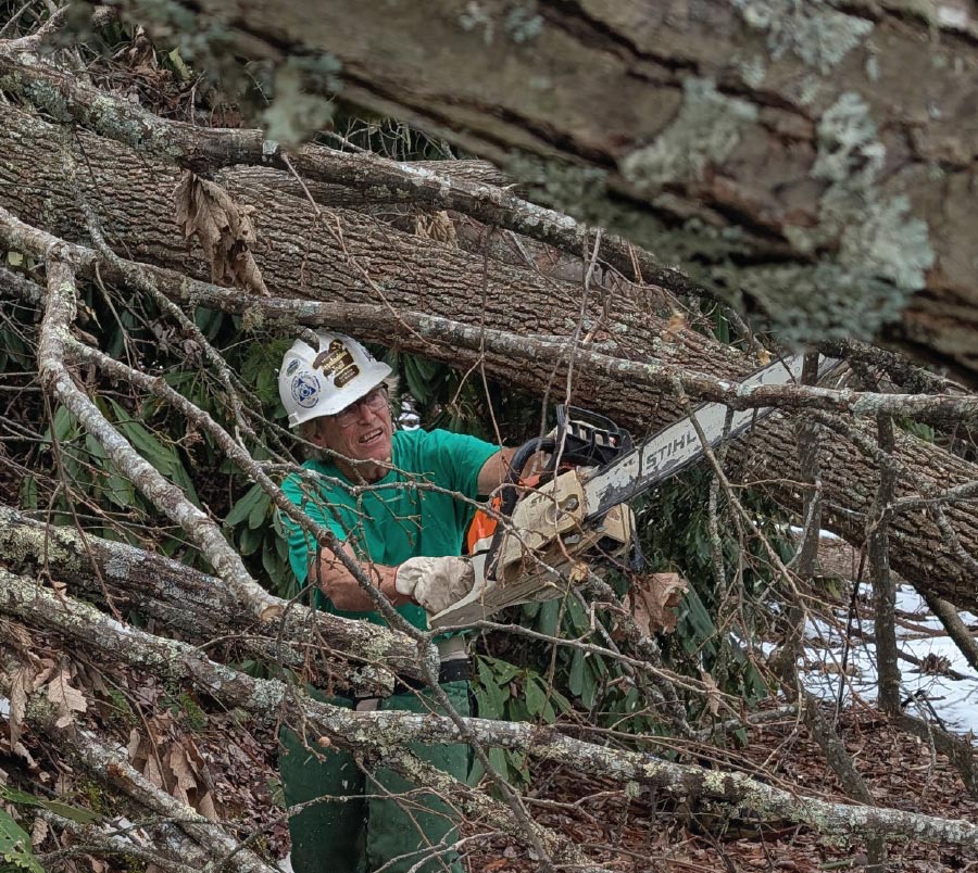 close up of man from Temple Hill Gap, Tennessee crew in between branches with chainsaw