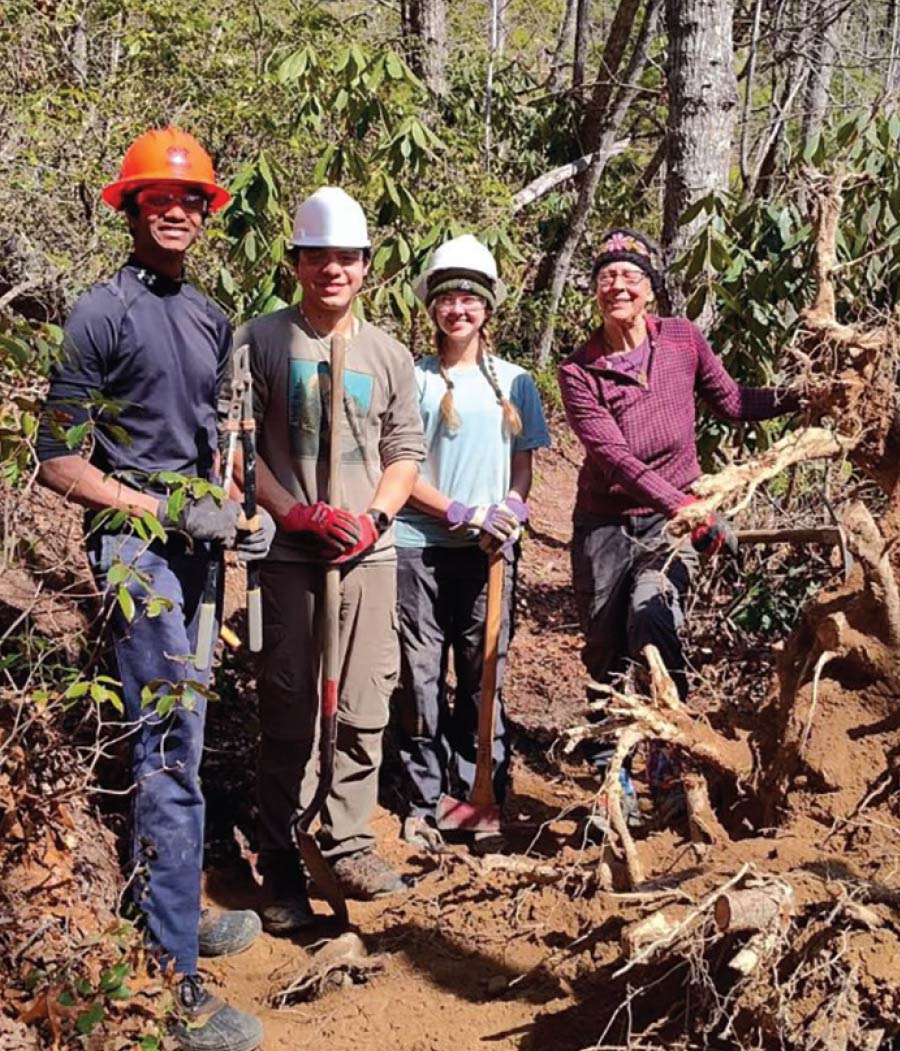dedicated volunteers and professional staff smiling for group photo while holding tools