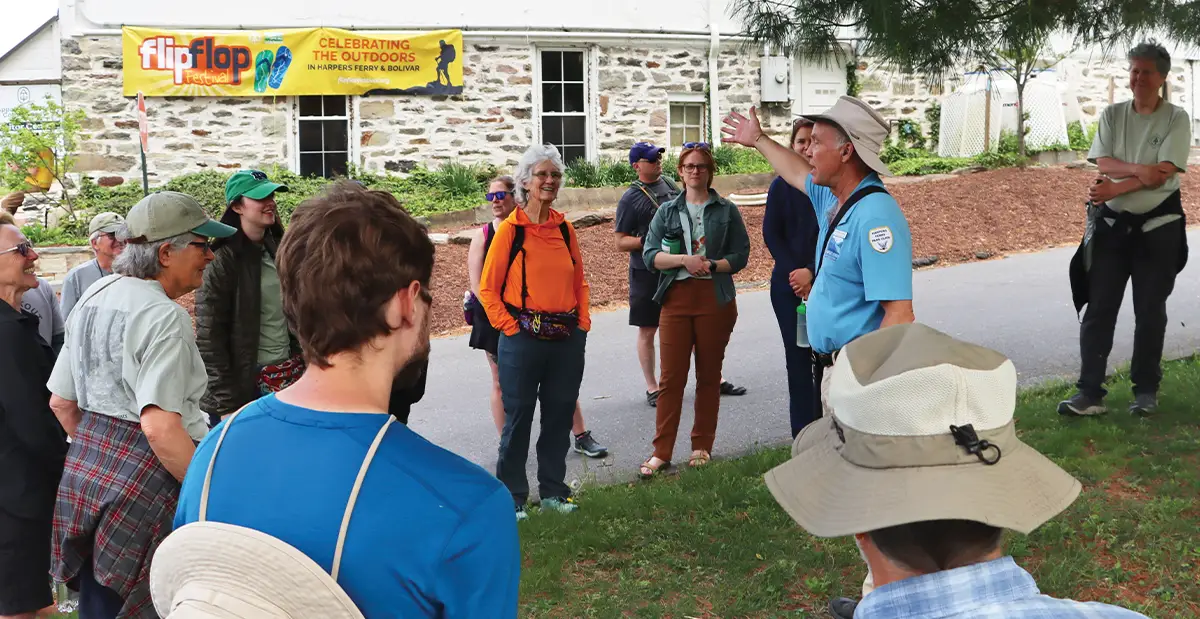 Group of hikers listening to a guide outdoors.
