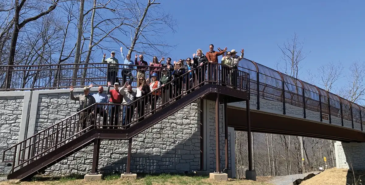 Group of people waving from a modern pedestrian bridge.