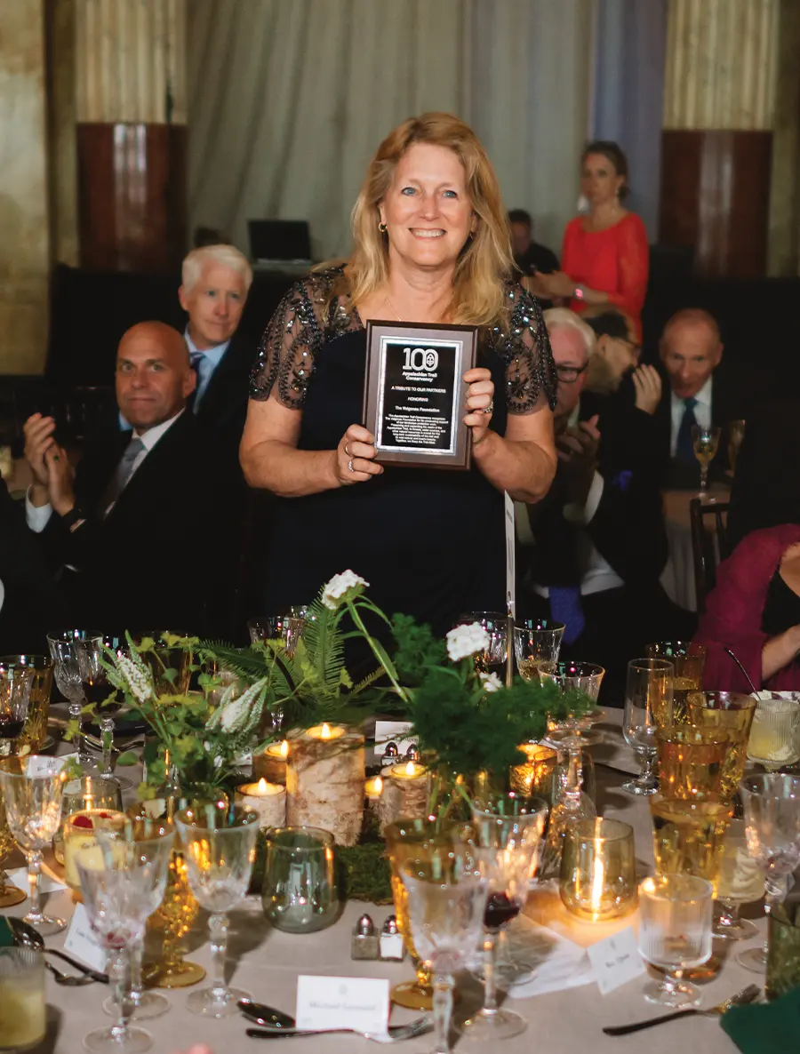 Woman holding an award plaque at a formal event.