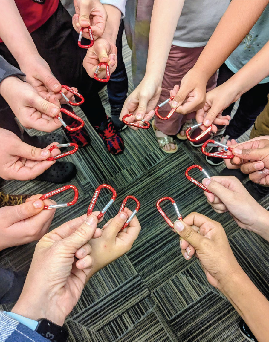 group of hands holding carabiners creating a circle