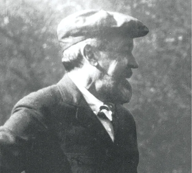 Black-and-white photo of a bearded man in a cap and jacket, shown in profile while outdoors.